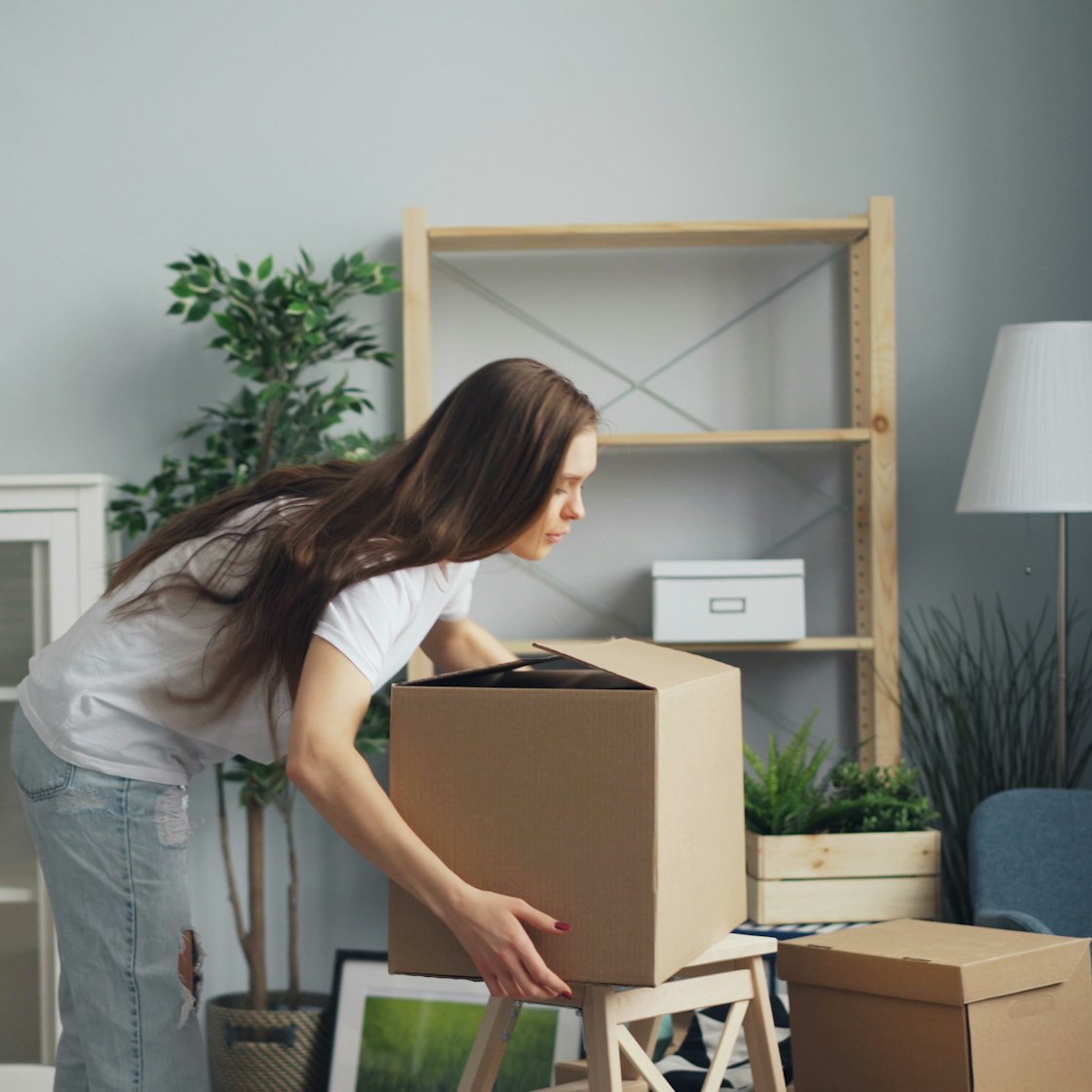 Woman moving packed boxes in a living room during a local Dallas move